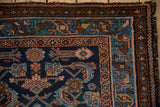 Corner of vintage Persian Mehriban rug shows Herati motif, sapphire field, brown, blush borders, and worn fringe.