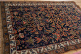 Kurdish Bijar rug detail: madder red floral cross-sections on a cobalt blue field, ivory border.