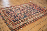 Vintage Hamadan rug detail with worn intricate border, navy field, and ruby red patterns.