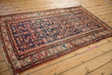 Vintage Hamadan rug corner, highlighting ruby red, navy Herati pattern, and secure fringe.