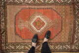 Traditional Hamadan rug corner with serrated leaf border, dusty coral field, and wear.
