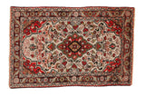 Vintage Dargezine rug with a shield medallion on a floral field of cherry red, ivory, and seafoam green.