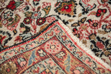 A vintage Persian rug's folded corner reveals the dense floral pile and hand-knotted foundation.