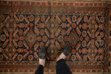 Antique Persian Belouch rug with a Herati-inspired geometric field in navy, rust, and brown.