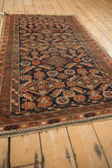 Antique Belouch rug with Herati-inspired serrated geometric motif in rust, navy, and brown.