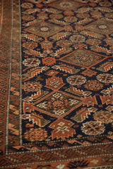 Antique Belouch rug's serrated geometric pattern in deep navy, rust, and ivory tones.