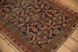 Time-softened, sharp geometric relief of an antique Belouch rug in navy and rust.