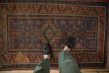 Antique Belouch rug with geometric finned floral field, hook and latch medallion, and serrated border.