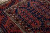 Belouch rug detail: brick red germinating plants and navy hook-and-latch designs.