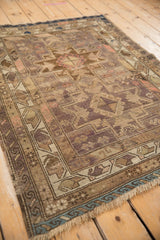 Geometric serpent motifs and boteh border on textured pile of vintage Caucasian rug.