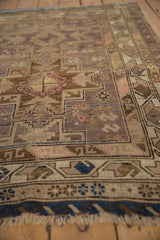 Vintage Caucasian rug detail showing geometric pinwheel guls, hook motifs, and textured dusty mauve pile.