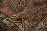 Rolled edge of the vintage Caucasian rug, highlighting the intact side cord selvage and textured brown and beige pile.