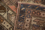 Vintage Caucasian rug's hand-knotted texture, dusty mauve, indigo blue geometrics, and fringe.