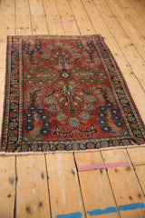 Vintage German Sarouk rug corner with cherry red field, floral border, and tattered fringe.