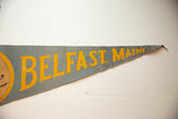Light blue-gray felt pennant showing yellow 'Belfast, Maine' text and frayed tip.