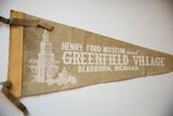 Angled view of the vintage Henry Ford Museum felt flag showing its printed graphics and side ties.