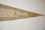 A small tear shown below the Greenfield Village text on the vintage felt pennant.