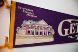 Screen-printed graphic of the Gettysburg National Museum on textured purple felt with yellow trim.