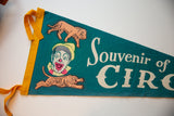 Vintage felt circus pennant showing yellow binding, grinning clown, lion, and tiger graphics.