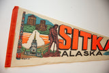 Angled view of the Sitka Alaska felt pennant's vibrant orange binding and detailed retro graphics.
