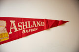 Vintage red felt Ashland Oregon pennant, featuring cream text and soft folds at its pointed end.