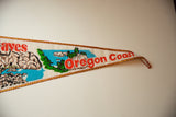 The pointed tip of the Oregon Coast pennant with red text and gold trim.