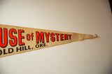 Pointed tip of the tan felt flag with red and black 'of MYSTERY' lettering.
