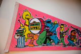 Vintage pink felt pennant with marching Sesame Street characters playing instruments.