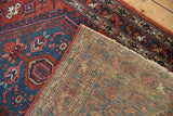 Traditional Hamadan rug corner, red and blue geometric pile with hook motifs, showing reverse.