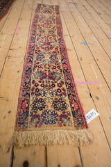 Intricate repeated floral petals on antique Kerman runner, cochineal red, navy, and apricot shades.
