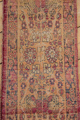 Antique Kerman fragment with cochineal red and navy floral motifs, prominent wear, and exposed foundation.