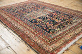 Geometric red, ivory Malayer rug border and worn navy Herati field with tattered edges.