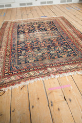 Worn navy and red Herati pattern and tattered fringe on a vintage Malayer rug.