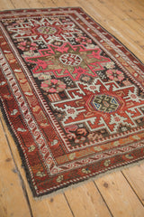 Caucasian rug detail with geometric patterns, arrowed florals, pink, burgundy, and brown tones.