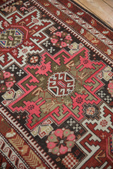 Pink, burgundy, and charcoal geometric patterns with wave border on a vintage Caucasian rug.