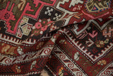 Textured vintage Caucasian rug with reciprocating wave border and stylized floral elements.