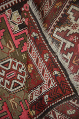 Geometric border and fringe detail of a vintage Caucasian rug with burgundy, charcoal, white.