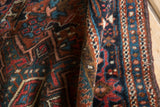 Thick pile and geometric hook and latch patterns of a Karaja rug in madder, teal, and brown.
