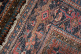 Geometric Karaja rug border detail featuring navy, madder red, and dusty teal with fringe.