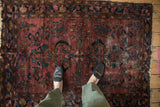 Vintage Persian Lilihan rug's central floral motif, scrolled boteh, abrashed plum, and teal.