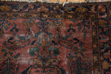 Worn plum field of a vintage Lilihan rug, with dusty teal floral pattern and tattered fringe.