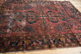 Detail of vintage Persian Lilihan rug: plum, dusty teal, and copper floral motifs with visible wear.