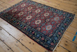 Vintage Lilihan rug corner: deep blue border with emerald green floral motifs and cherry red field.