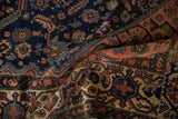 Textured fold of vintage Malayer rug, deep indigo field, and rust-toned Samovar border.