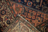 Vintage Malayer rug's woven foundation, tattered side, and blush, indigo, ivory patterns.
