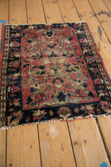 Vintage Lilihan rug corner showing worn red pile, visible foundation, and navy border.