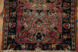 Vintage Lilihan rug corner, faded brick red field, navy border, visible knot heads, and white fringe.