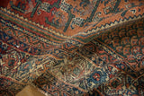 Textured section of vintage Persian Malayer rug with geometric vinery in deep red, blue, green.
