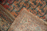 Vintage Malayer rug folded to reveal its brick red geometric pattern and woven foundation.