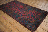Corner of vintage Mehreban rug, raspberry red field, sapphire blue patterned border, and natural fringe.
